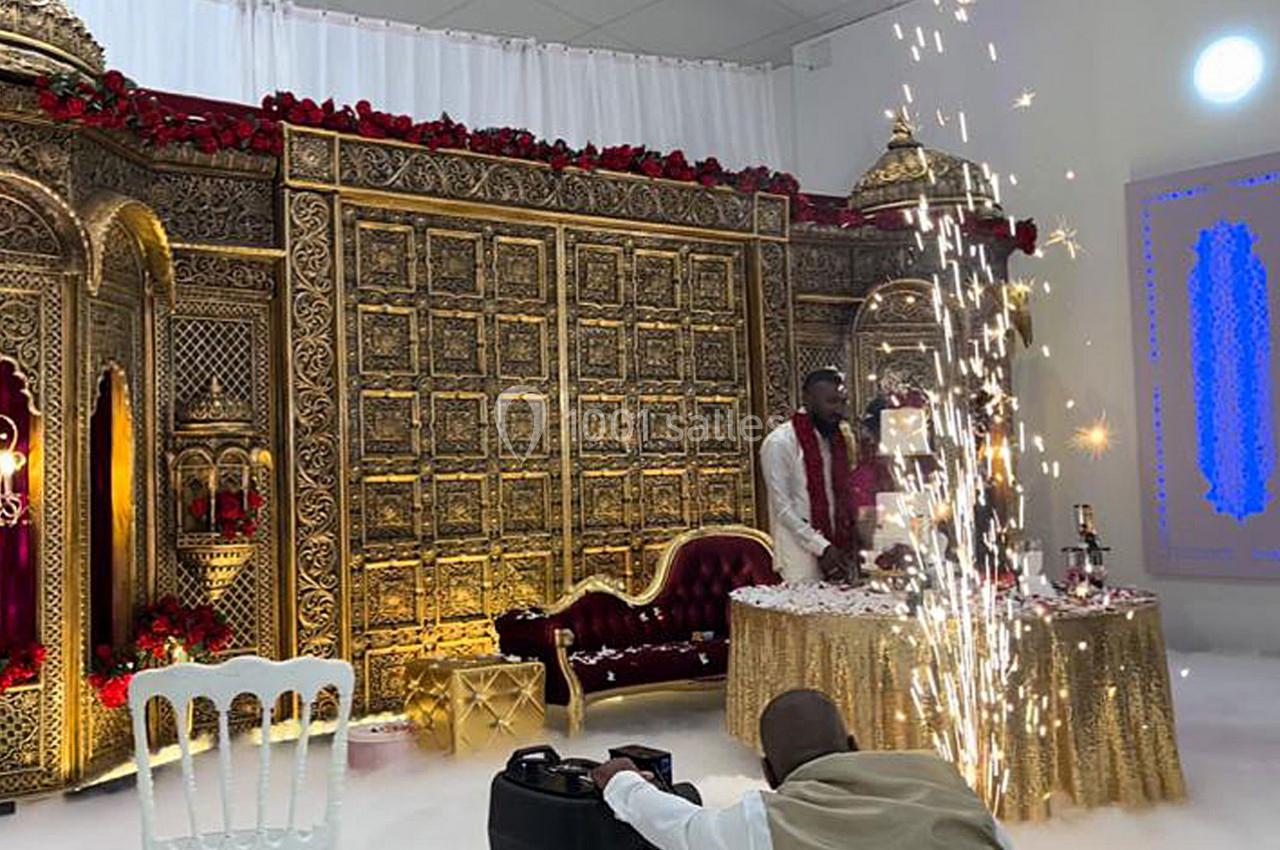 Décor doré richement orné avec un canapé rouge, une table festive et des étincelles dans une ambiance de célébration.