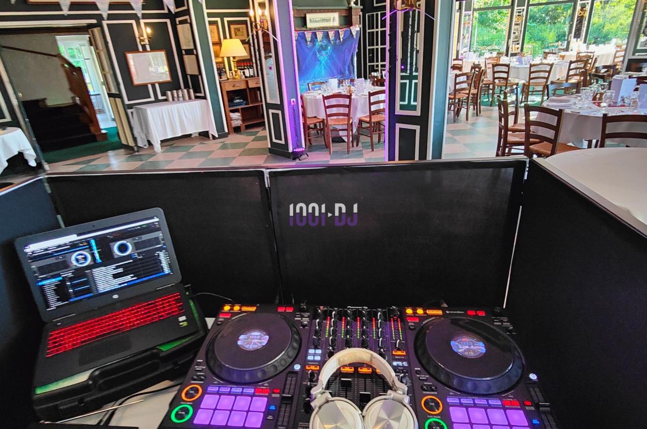 Poste de DJ avec platines, casque et ordinateur dans une salle décorée pour un événement festif.
