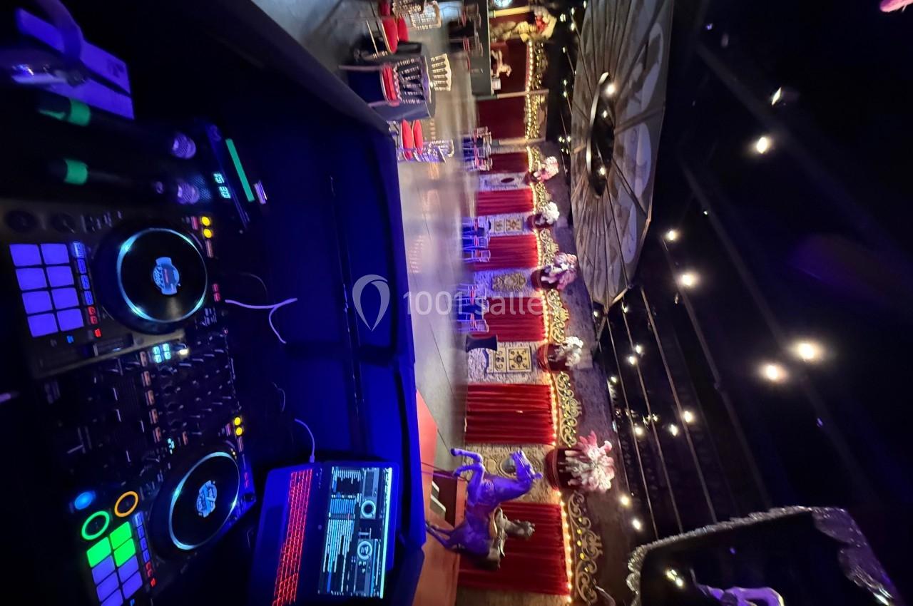 Vue d'une salle de spectacle décorée avec des lumières, des rideaux rouges et des éléments festifs, prise depuis une table…