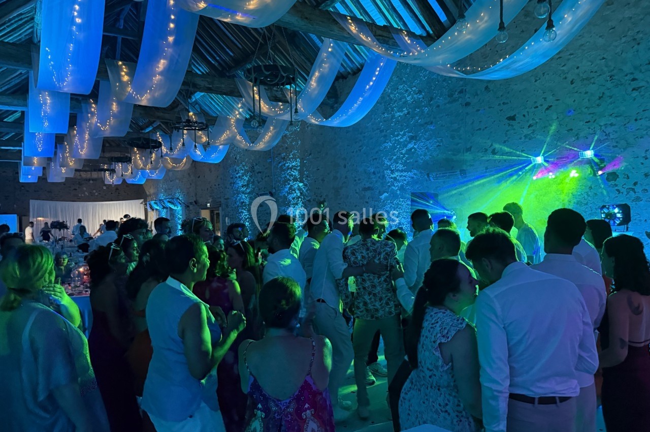 Groupe de personnes dans une salle en pierre éclairée par des lumières colorées lors d'une fête ou d'un événement.