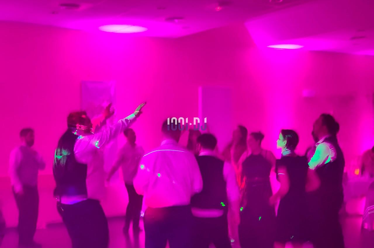 Des personnes dansent sous des lumières roses et violettes dans une salle sombre.