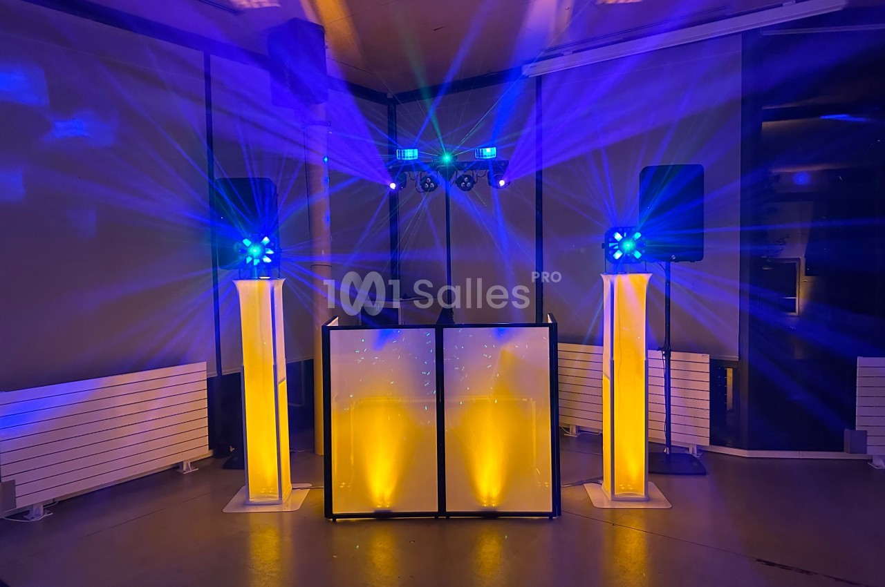 Installation de matériel de sonorisation et d'éclairage avec jeux de lumières colorées dans une salle sombre.