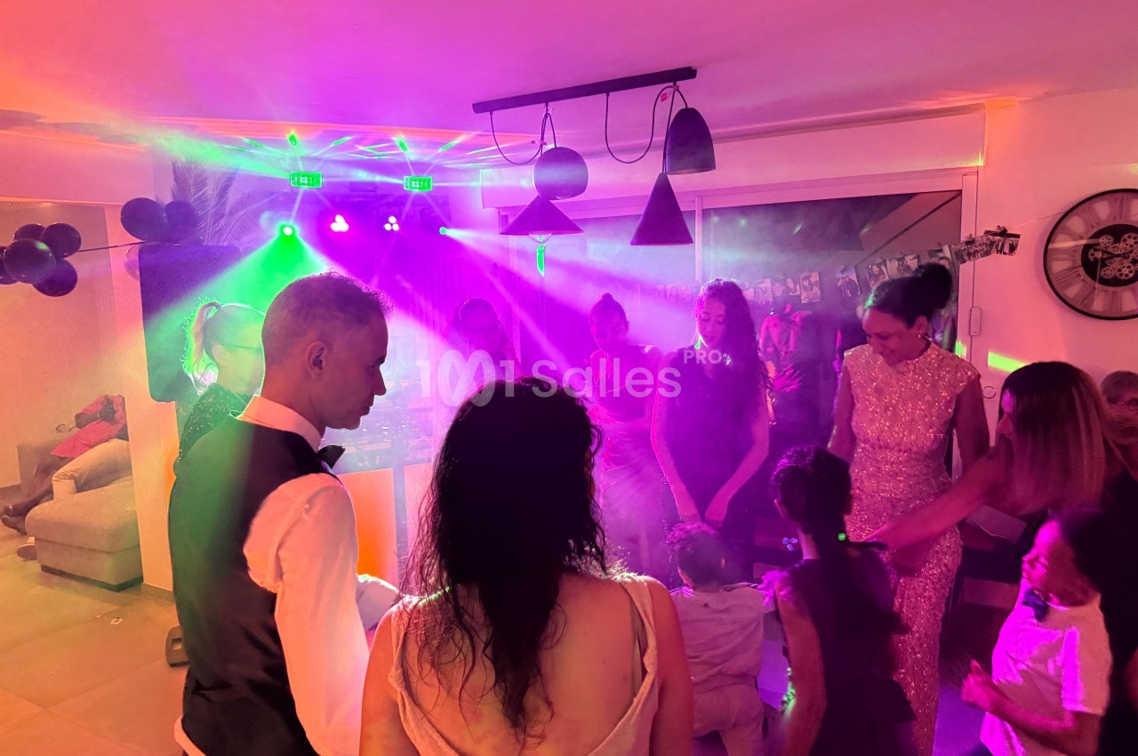Personnes dansant et discutant sous des lumières colorées dans une ambiance festive en intérieur.