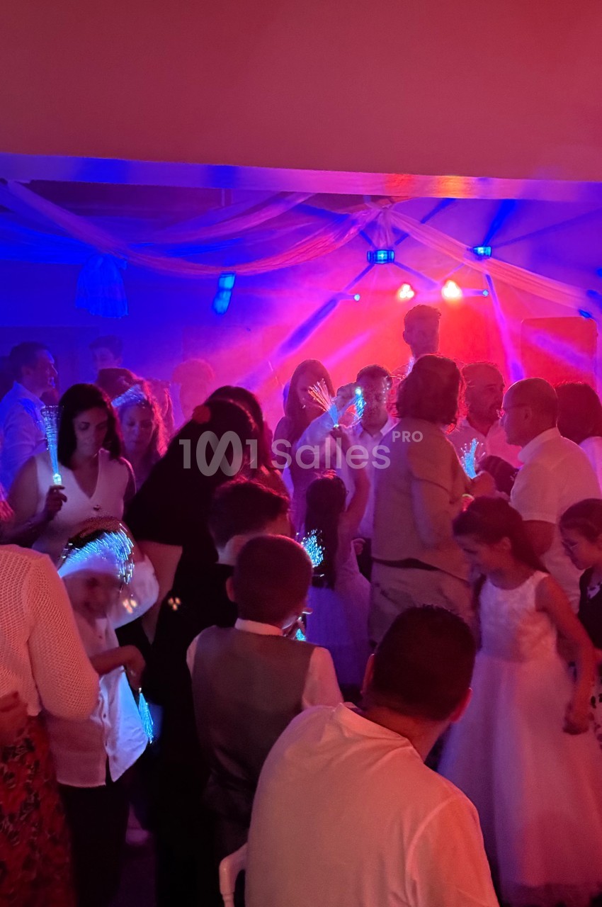 Groupe de personnes dansant sous des lumières colorées dans une ambiance festive en intérieur.