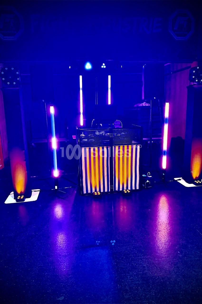 Installation de matériel de sonorisation et éclairage coloré dans une salle sombre, avec une table centrale.