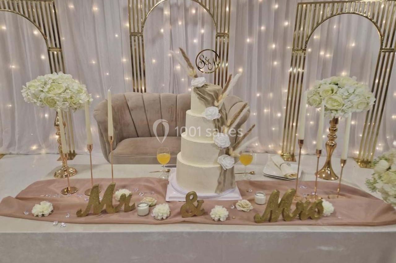 Gâteau de mariage à plusieurs étages décoré de fleurs séchées, entouré de bougies et d'arrangements floraux.