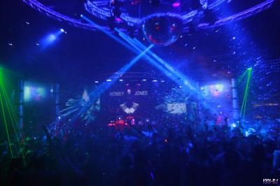 Des personnes assises à l'extérieur, regardant une présentation projetée sur un écran sous des guirlandes lumineuses.