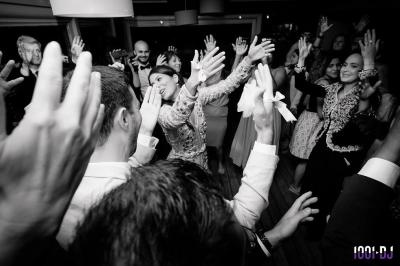 Des personnes assises à l'extérieur, regardant une présentation projetée sur un écran sous des guirlandes lumineuses.