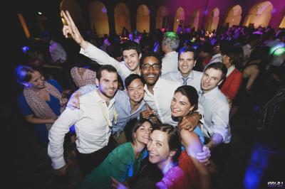 Des personnes assises à l'extérieur, regardant une présentation projetée sur un écran sous des guirlandes lumineuses.