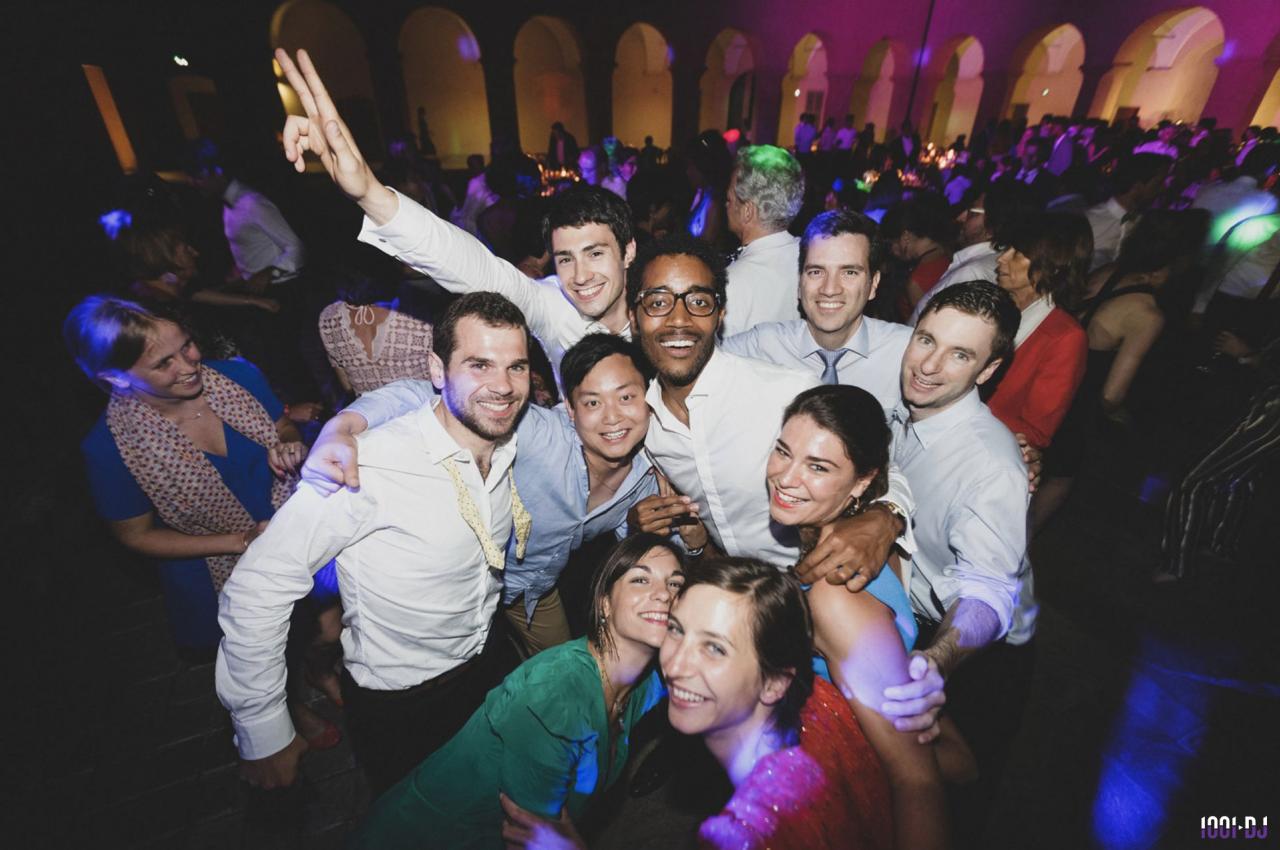 Un groupe de personnes souriantes posant ensemble lors d'une soirée dansante avec éclairage coloré.