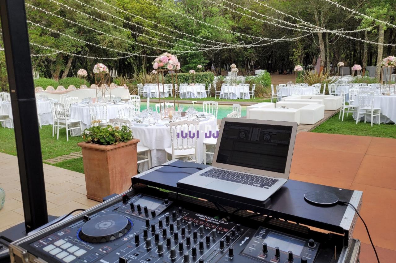 Table de mixage et ordinateur portable installés en extérieur, avec des tables décorées et des guirlandes lumineuses en…