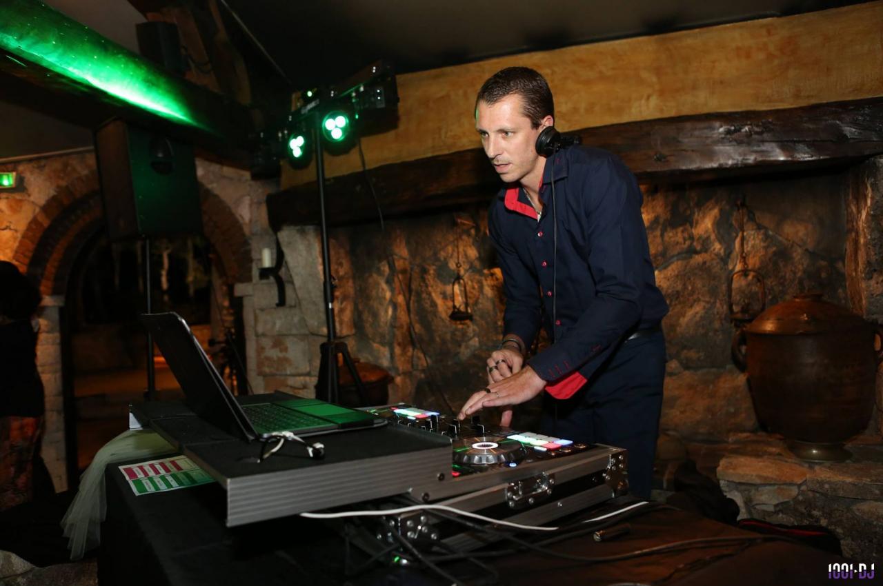 Un DJ mixe de la musique sur une console dans un cadre intérieur avec des murs en pierre.