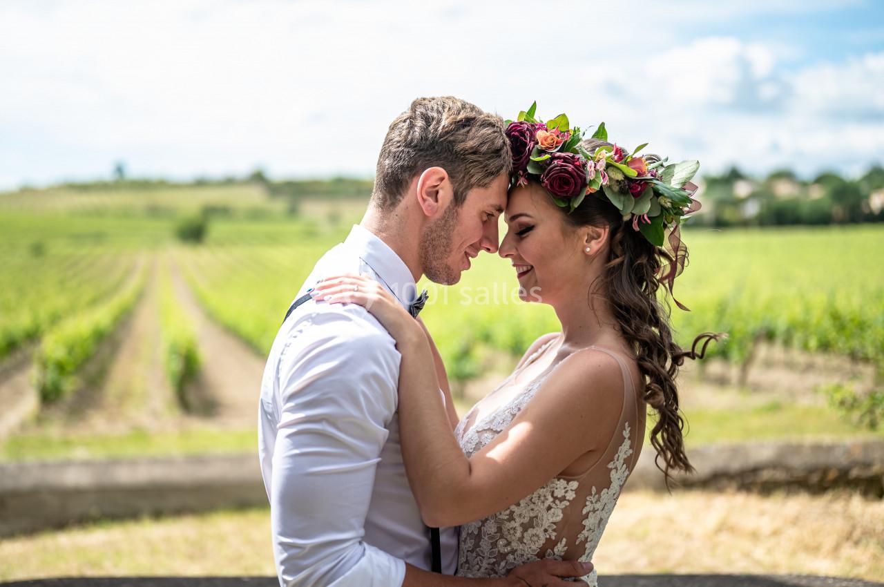 Location salle Malviès (Aude) - Château Guilhem #4 Un couple en tenue de mariage s'enlace dans un vignoble sous un ciel ensoleillé.