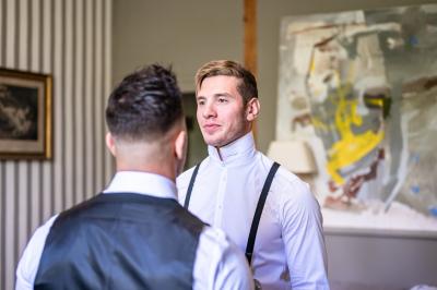 Miniature MARIE ET SON TEMOIN DANS UNE SUITE Un marié aide sa partenaire en robe de mariée à sortir d'une voiture ancienne décorée pour un mariage.