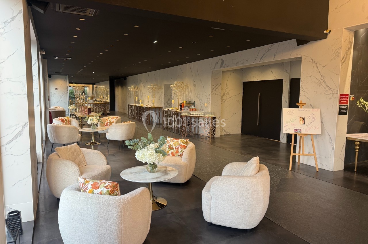 Espace intérieur moderne avec fauteuils arrondis, tables basses décorées de fleurs et comptoir en arrière-plan.