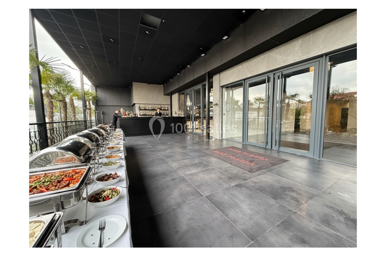 Buffet varié disposé sur une terrasse moderne avec vue sur des palmiers et un bar en arrière-plan.