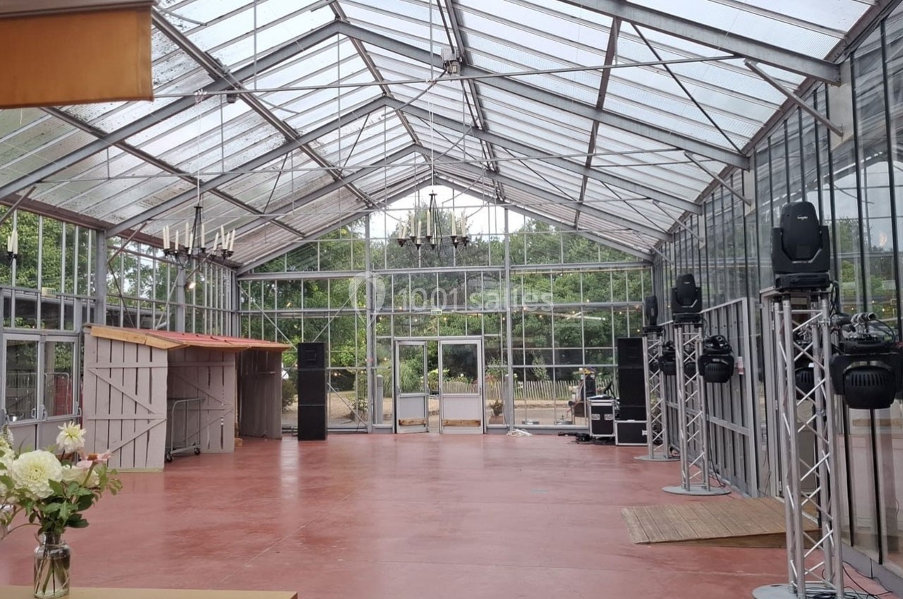 Intérieur d'une serre aménagée avec un sol rouge, des structures métalliques et des équipements d'éclairage.