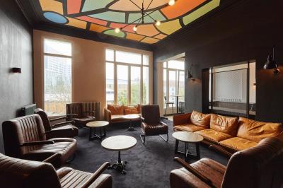 Salle de restaurant moderne avec murs en briques, tables en bois, chaises en cuir et éclairage tamisé.