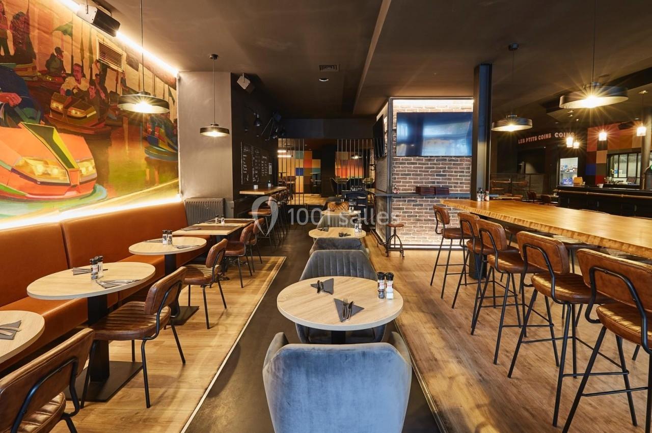Salle de restaurant moderne avec tables en bois, chaises rembourrées, bar en bois et fresque murale colorée.