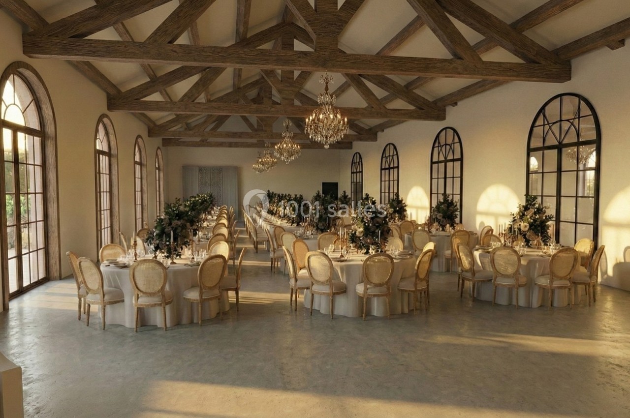 Salle de réception lumineuse avec des tables rondes décorées, des chaises élégantes et des poutres apparentes au plafond.