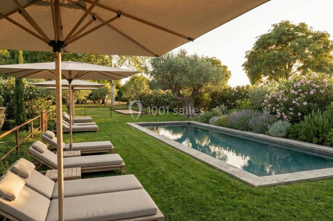 Chaises longues et parasols disposés autour d'une piscine entourée de pelouse et de végétation luxuriante.