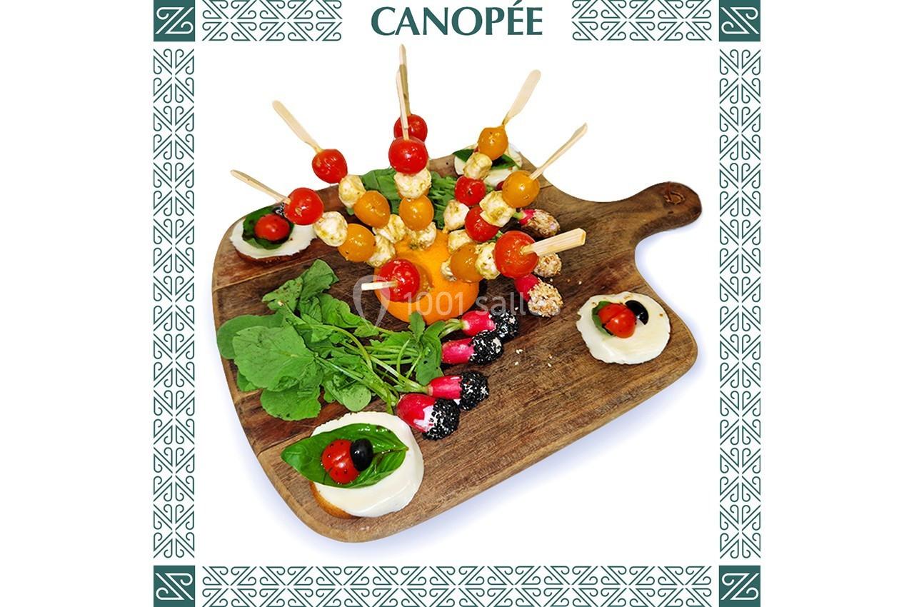 Plateau en bois avec brochettes de tomates cerises et fromage, accompagné de crudités et de sauces décorées.