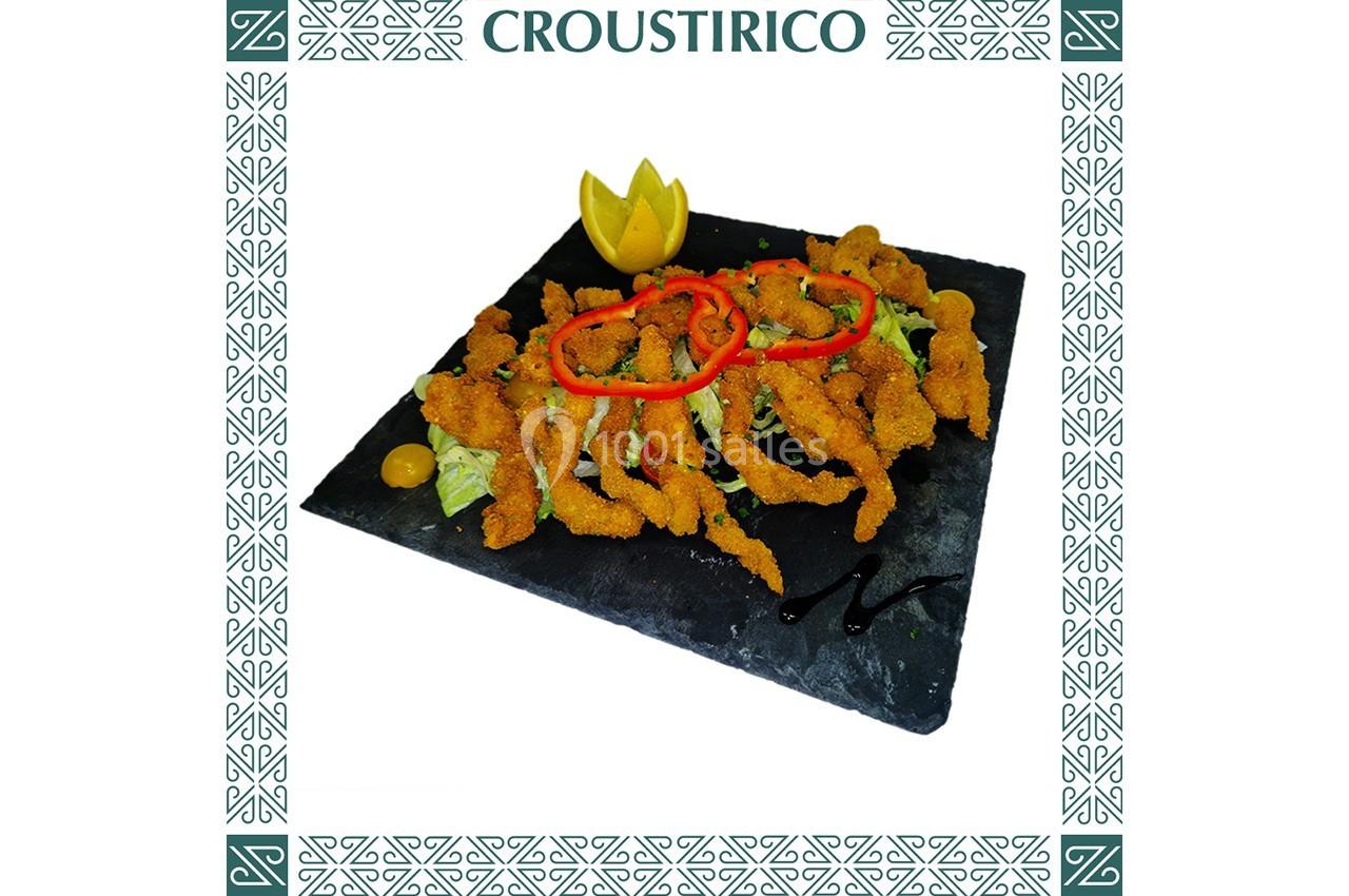 Assiette de beignets de poisson dorés sur lit de salade, décorée de rondelles de poivron et d'une garniture citronnée.