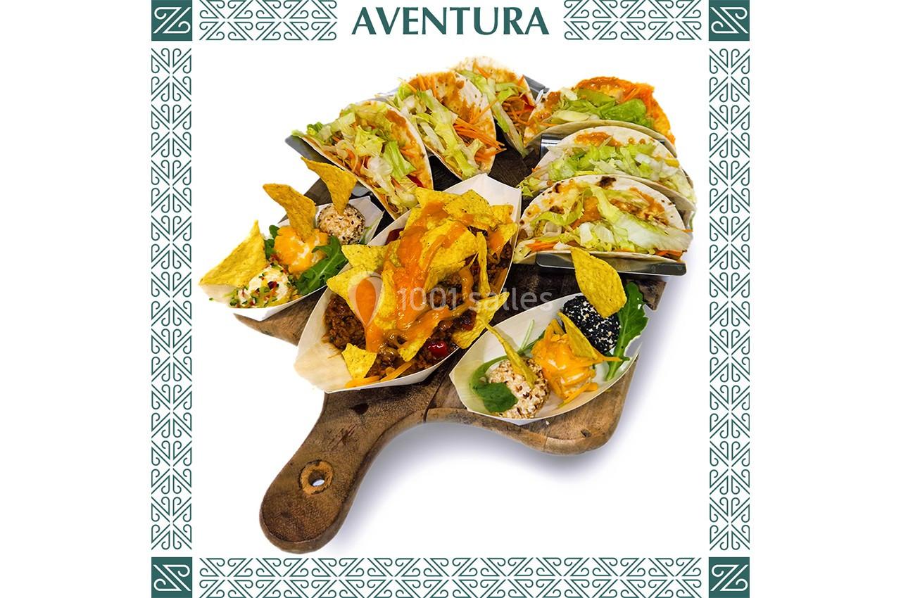 Plateau en bois garni de tacos variés avec garnitures colorées, présenté sur un fond décoratif.