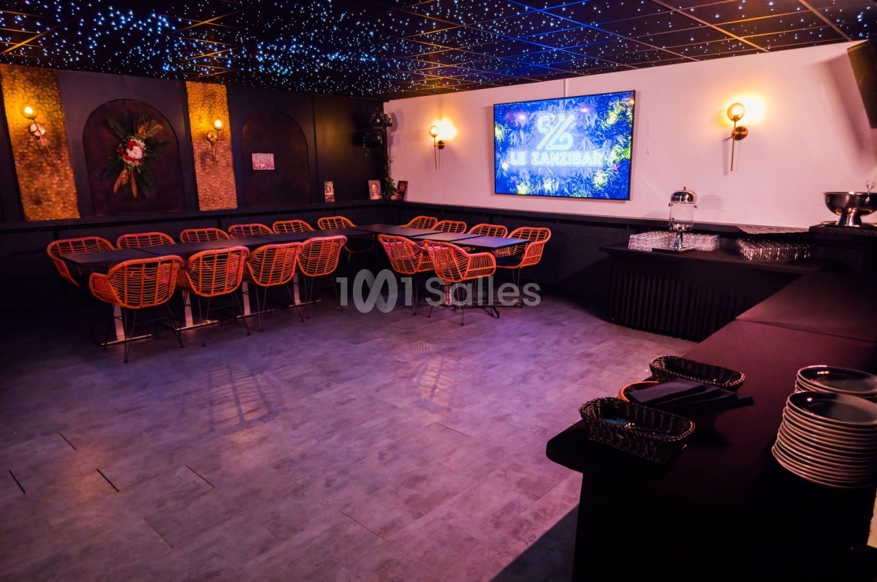 Salle aménagée avec des chaises en rotin, un écran de projection allumé et une table de buffet sur le côté.