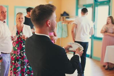 Miniature Edi Cappera #2 Un magicien sur scène tenant une baguette devant un accessoire éclairé dans un décor sombre.