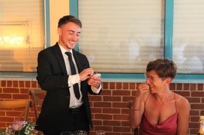 Miniature Edi Cappera #4 Un magicien sur scène tenant une baguette devant un accessoire éclairé dans un décor sombre.