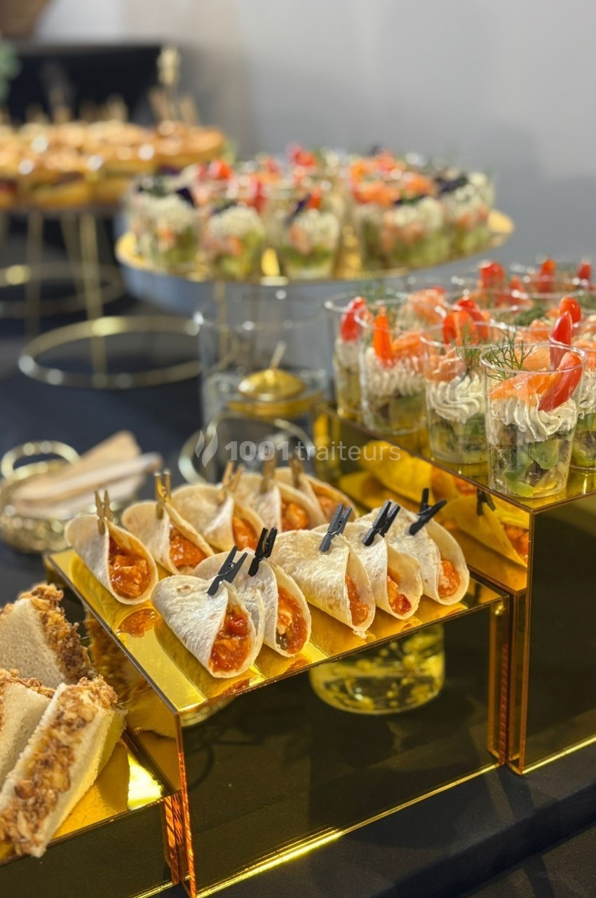 Plateau de buffet avec verrines, mini-wraps et amuse-bouches variés disposés sur des présentoirs dorés.