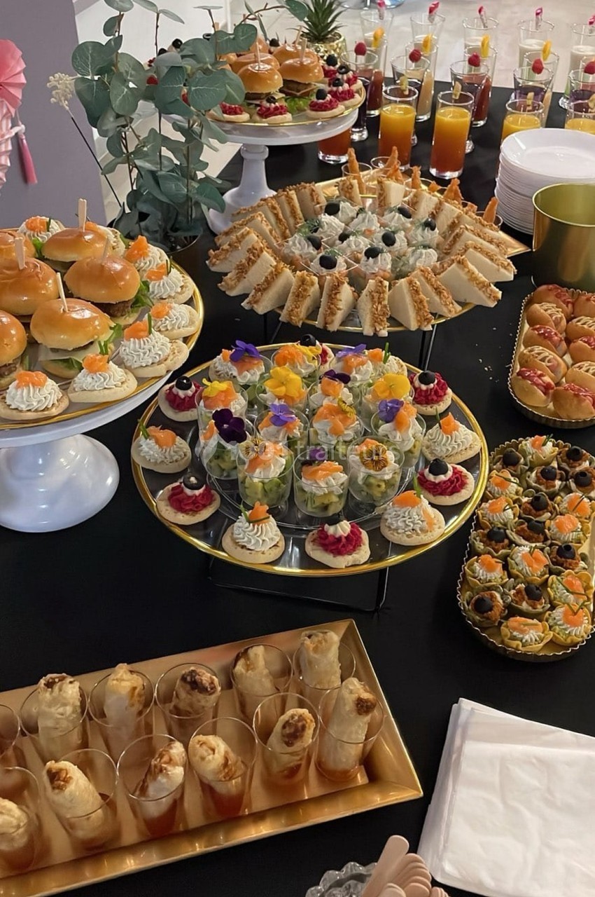 Buffet de pièces cocktail variées comprenant sandwichs, verrines, mini-burgers, feuilletés et jus de fruits.