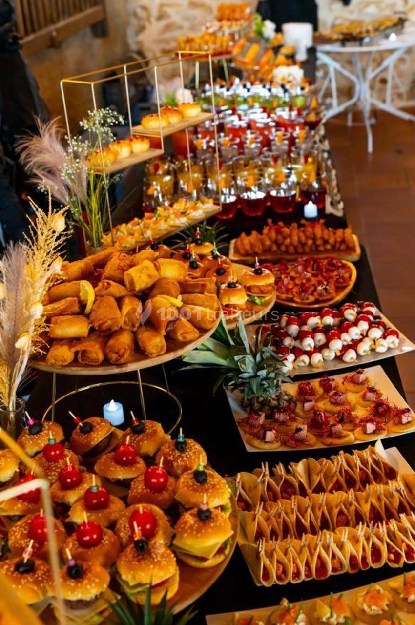 Buffet varié avec mini-burgers, rouleaux de printemps, verrines, brochettes et autres amuse-bouches colorés.