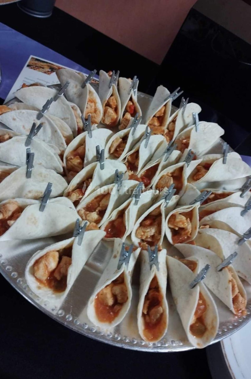 Plateau circulaire garni de mini-tacos garnis de poulet et sauce, maintenus par de petites pinces métalliques.