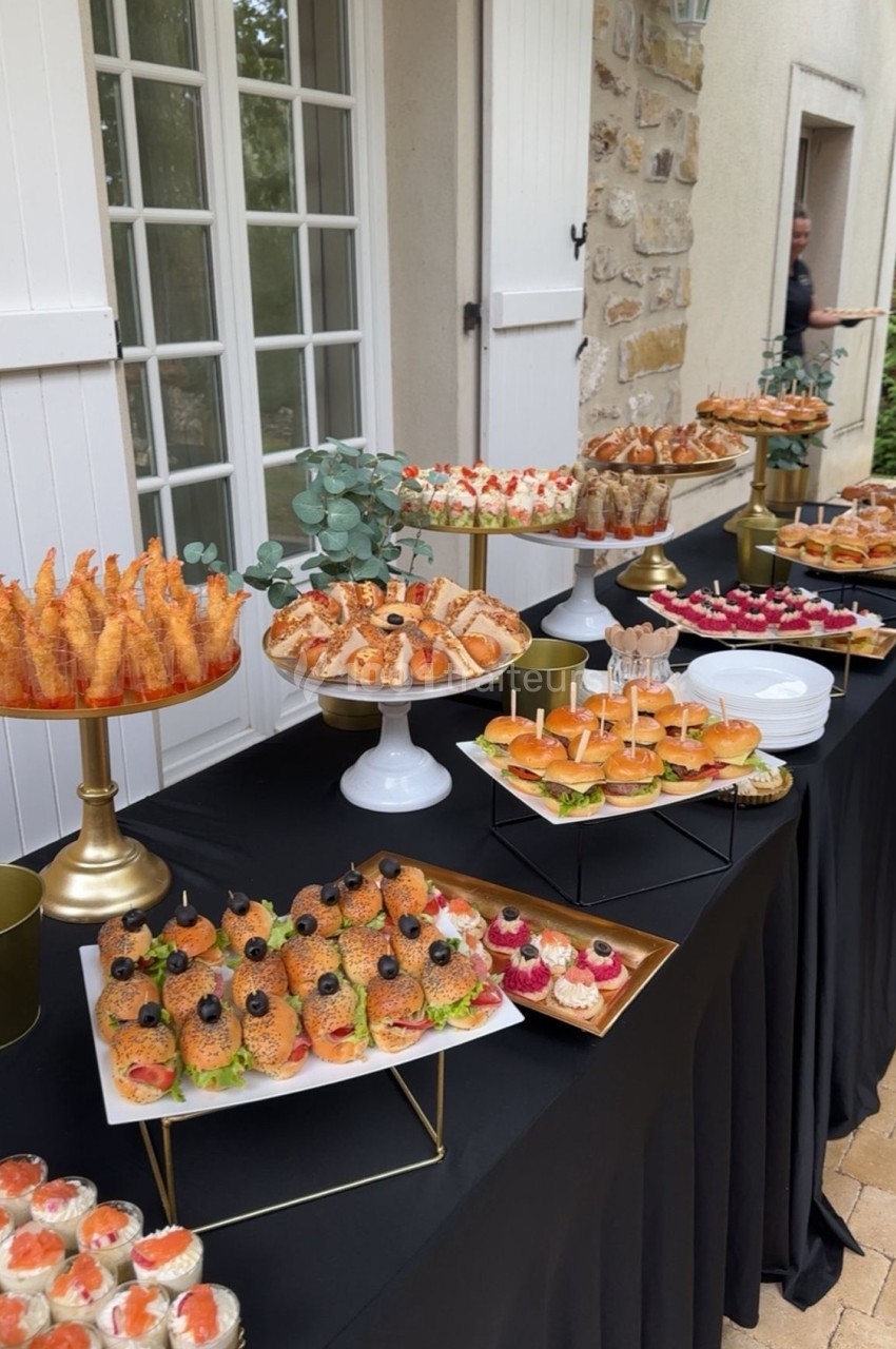 Buffet extérieur avec une variété de bouchées salées et sucrées présentées sur des plateaux élégants.