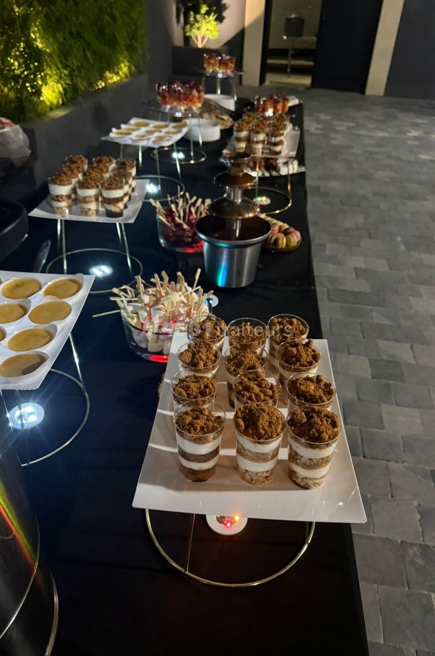 Buffet de desserts variés comprenant verrines, sucettes et autres douceurs disposés sur une table noire.