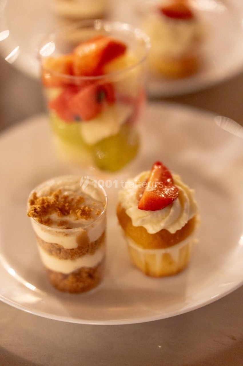 Deux verrines dessert et un cupcake décoré de fraises, présentés sur une assiette blanche.