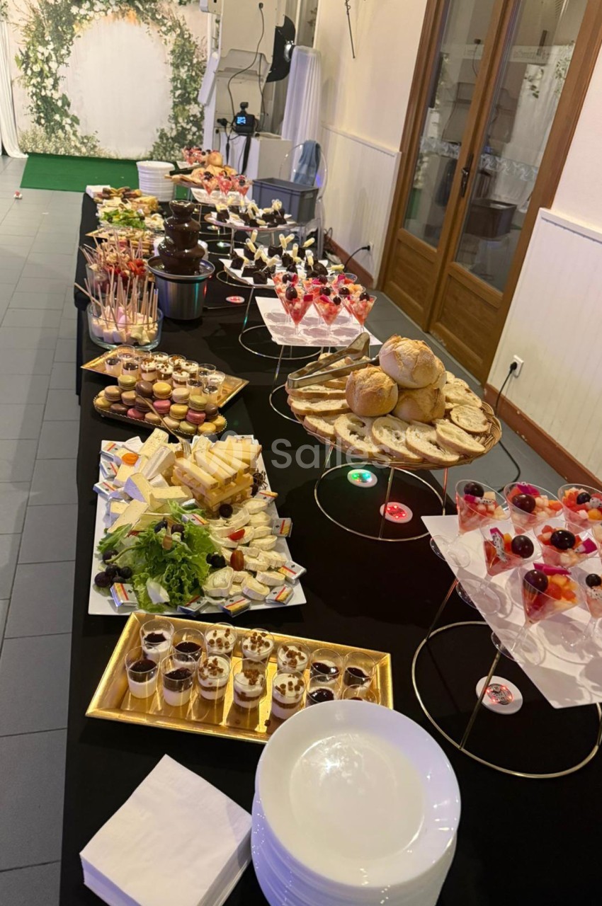 Buffet varié avec desserts, fromages, pains et fontaine de chocolat, présenté sur une longue table noire.