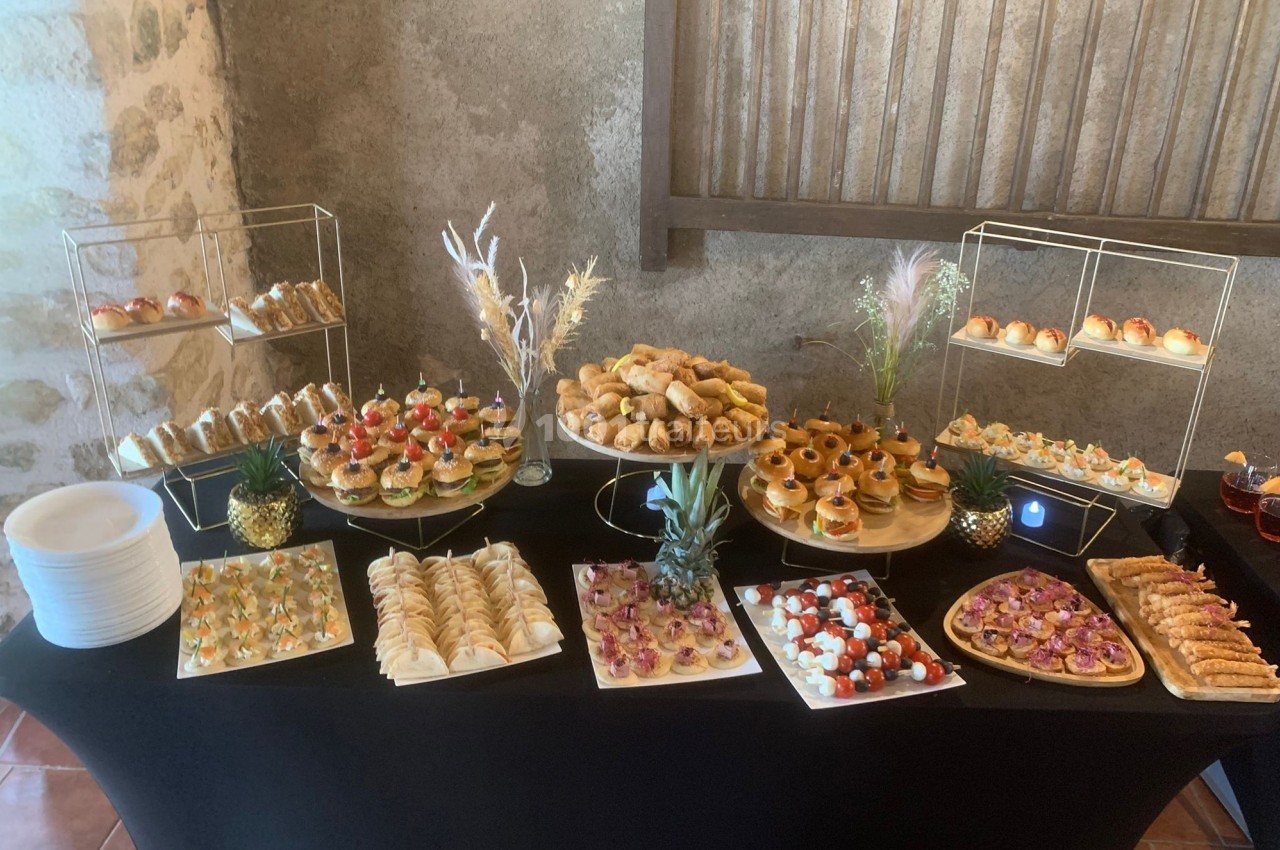 Buffet de pièces apéritives variées disposées sur une table noire, avec des présentoirs et décorations.