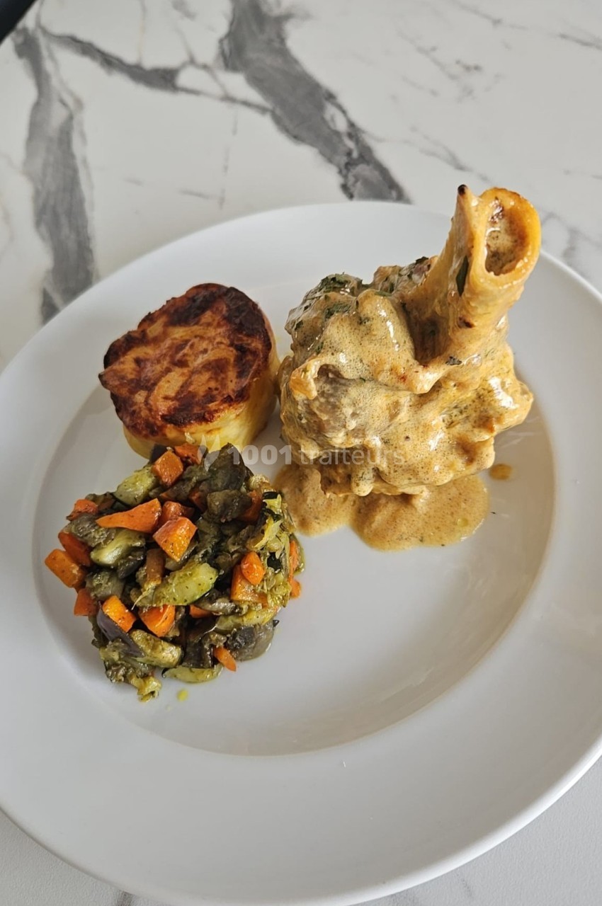 Assiette composée d'un osso buco en sauce, d'un gratin de pommes de terre et de légumes sautés colorés.