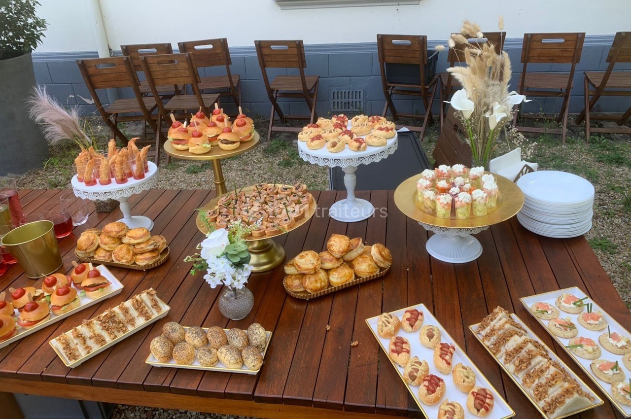 Buffet en extérieur avec une variété de plats salés et sucrés disposés sur une table en bois.