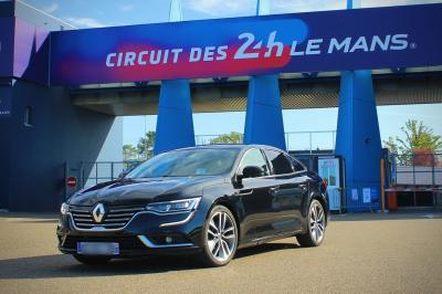 Voiture noire garée sur une place pavée, entourée de bâtiments historiques en arrière-plan.