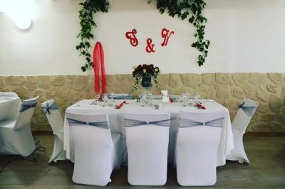 Salle spacieuse avec sol en parquet, murs en pierre et poutres blanches apparentes, éclairée par des lumières modernes.