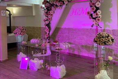 Salle spacieuse avec sol en parquet, murs en pierre et poutres blanches apparentes, éclairée par des lumières modernes.