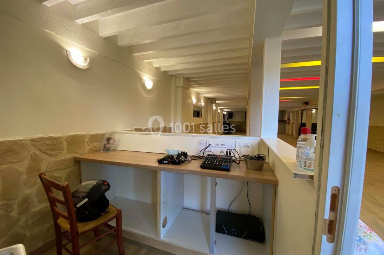 Bureau en bois avec chaise, équipements électroniques et étagères, situé dans une pièce aux murs clairs et poutres…