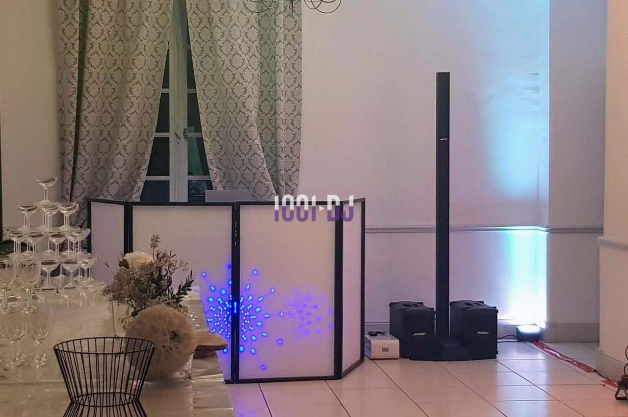 Table de mixage éclairée avec des motifs lumineux, entourée de colonnes sonores dans une salle décorée de rideaux et…