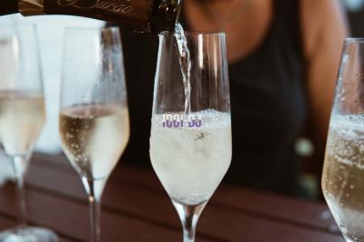 Miniature DJ Le Havre (Seine-Maritime) - Dj Tennessee #14 Un verre de champagne est rempli depuis une bouteille, entouré de trois autres verres sur une table en bois.