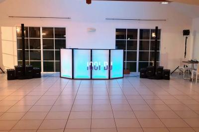 Un verre de champagne est rempli depuis une bouteille, entouré de trois autres verres sur une table en bois.