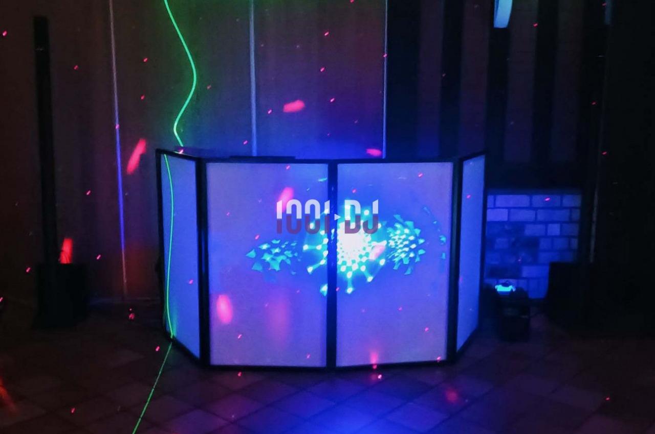 Pupitre de DJ éclairé avec des lumières colorées et des lasers dans une pièce sombre.